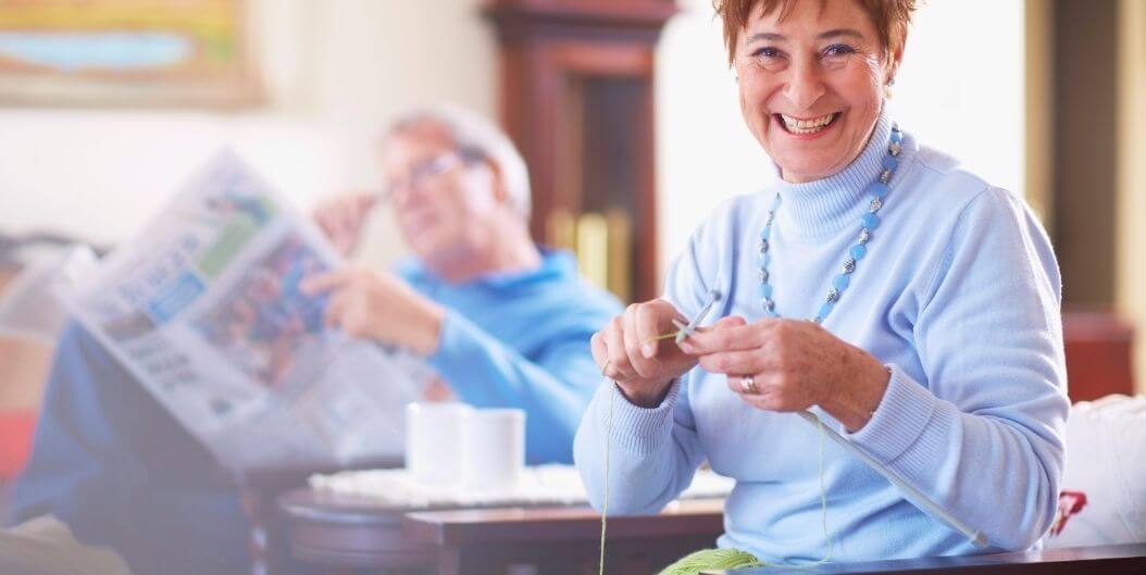 Elderly Woman Smiling While Knitting in Her Living Room at an Independent Living Facility