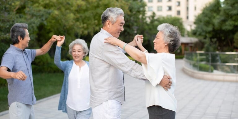 Elderly Couples Dancing Joyfully Outdoors in the Garden at Independent Living Facility
