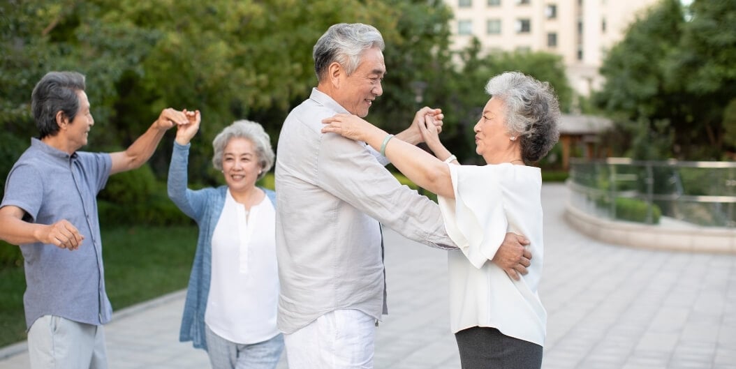 Elderly Couples Dancing Joyfully Outdoors in the Garden at Independent Living Facility