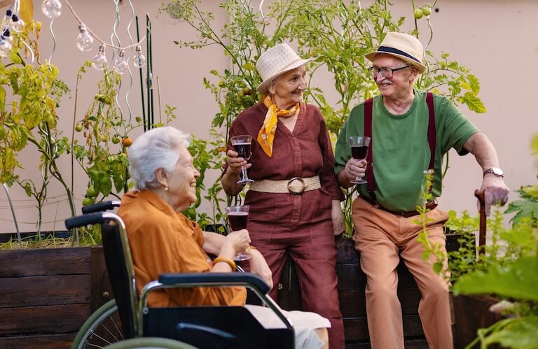 Three Elderly Friends Enjoying Wine in a Garden at an Independent Living Facility