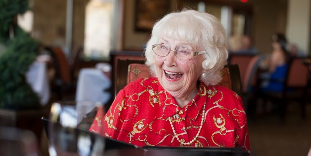 Elderly Woman Laughing Joyfully During Dinner at Independent Living Facility